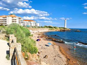 ein Strand mit einem Leuchtturm im Hintergrund mit einem Gebäude in der Unterkunft Le Lagon Bleu in Les Sables-dʼOlonne