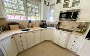 a white kitchen with white cabinets and windows at Jacks Place 3bd by ZenBreak in Saint Peter