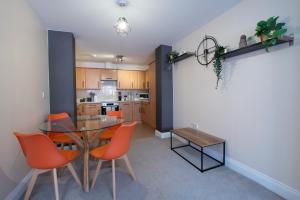 a kitchen and dining room with a glass table and orange chairs at 1-Bed Apartment in Bournemouth centre in Bournemouth