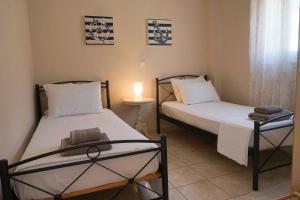 two twin beds in a room with a lamp at Myrtos Cottages Kefalonia in Divarata