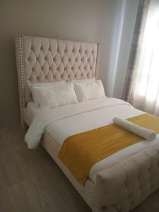 a white bed with a large white headboard in a bedroom at 1255 Palm Ridge Estate in Vipingo