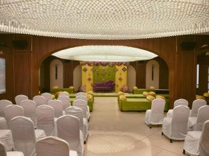 a room with white chairs and a room with a couch at Hotel Shreeji Vatika, Airport Road in Surat