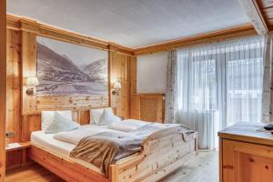 a bedroom with a large bed with a picture on the wall at Hotel Alpenstolz in Mieders