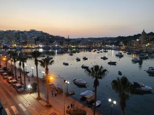 a harbor with boats in the water at night at Bay Seafront Apartment in Marsaskala