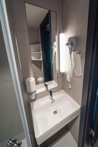 a bathroom with a white sink and a mirror at Komandu Sporta Spēļu Halles viesnīca in Rīga