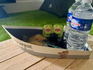 a container of food and a bottle of water on a table at Les Flots de Barzan Expérience Glamping Insolite in Barzan