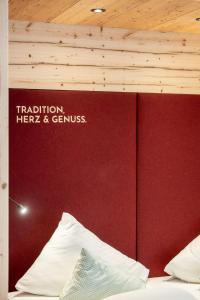 a bedroom with a red wall and a bed with white pillows at Hotel Alpenstolz in Mieders