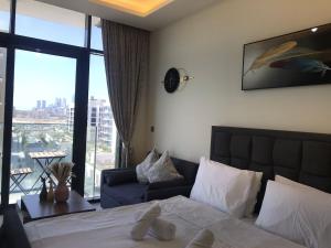 a bedroom with a bed and a couch and a window at Pet Free Studio Apartment Close Downtown Fast Wi-fi in Dubai