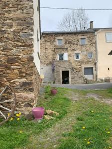 an old stone building with a stone wall at La petite maison dans le Sidobre in Fontrieu
