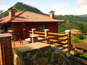 una casa roja con una valla de madera delante de ella en La Portiella en Bueres