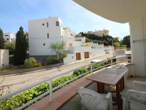 ein Balkon mit einem Holztisch und weißen Gebäuden in der Unterkunft Apartamento acogedor con piscina, WiFi y garaje cerca de la playa de La Farella, Llançà - ES-228-8 in Llança