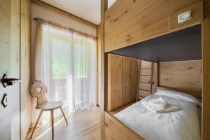 a bedroom with a bunk bed and a chair and a window at Chalet Belvedere - Dolomiti Skyline in Cortina dʼAmpezzo