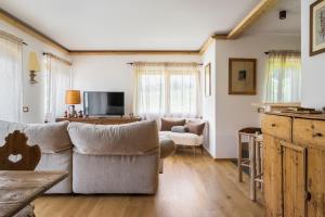 a living room with a couch and a tv at Chalet Belvedere - Dolomiti Skyline in Cortina dʼAmpezzo