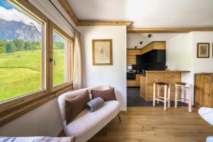 a living room with a couch and a kitchen at Chalet Belvedere - Dolomiti Skyline in Cortina dʼAmpezzo