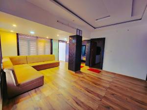 a living room with a yellow couch and wooden floors at Casamia Garden in Batheri