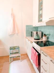 a kitchen with white cabinets and green tiles at Beautiful home close to the sea and city center in Helsinki