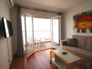 a living room with a couch and a balcony with a table at LLANÇÀ 8 LATERAL - Apartamento con vistas al mar, parking y Wifi. - ES-228-55 in Port de la Selva