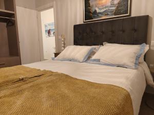 een groot bed met witte lakens en blauwe kussens bij Alpha 4 in Nafplio