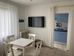 a dining room with a table and a tv on a wall at CUXKieker - Moderne Ferienwohnung mit Pep in Cuxhaven-Sahlenburg, WLAN, Parkplatz und Gartenblick, nah am Nordseestrand und Wernerwald in Cuxhaven +15 photos