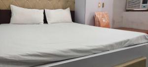 a bed with white sheets and pillows in a room at Hotel O Home Crystal Cottage Home Stay in Ayodhya