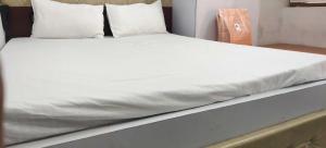 a bed with white sheets and pillows on it at Hotel O Home Crystal Cottage Home Stay in Ayodhya