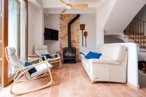 ein Wohnzimmer mit weißen Stühlen und einem Kamin in der Unterkunft Alojamiento rural La Mula en pleno corazón de la montaña de Alicante in Patró
