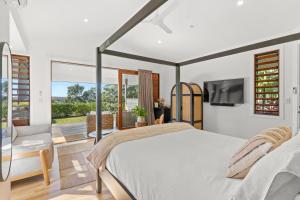 EwingsdaleにあるTranquil Byron Bay Villa, Cape Vue 1のベッドルーム(ベッド1台、テレビ、バルコニー付)