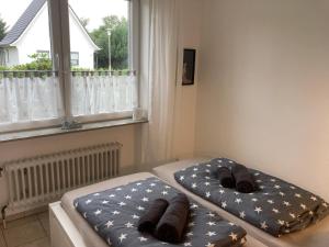 two beds in a room with a window at CUXKieker - Moderne Ferienwohnung mit Pep in Cuxhaven-Sahlenburg, WLAN, Parkplatz und Gartenblick, nah am Nordseestrand und Wernerwald in Cuxhaven