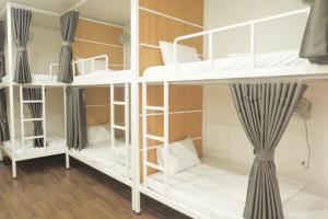 a room with white bunk beds with a curtain at Euphoria Cat Ba Homestay in Cat Ba