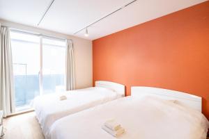 two beds in a room with an orange wall at 難波民泊301 in Osaka