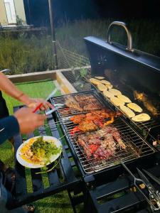 une personne qui cuisine de la nourriture sur un grill avec une assiette de nourriture dans l'établissement Tràng An Sunny River Homestay, à Ninh Binh