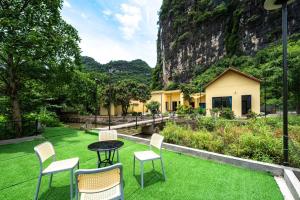 d'une terrasse avec des chaises et une table sur une pelouse. dans l'établissement Tràng An Sunny River Homestay, à Ninh Binh