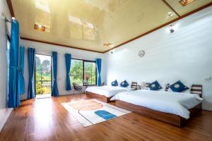 - 2 lits dans une chambre avec des rideaux bleus dans l'établissement Tràng An Sunny River Homestay, à Ninh Binh 45 autres photos