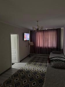 a living room with a couch and a tv on a wall at Ахметова 10 in Almaty