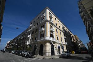 ein großes weißes Gebäude, vor dem Autos parkten in der Unterkunft La finestra sul Campanile Luxury Suite & Loft in Bari