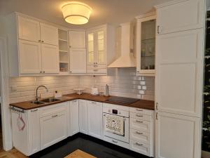 a white kitchen with white cabinets and a sink at Rumianka in Rumia