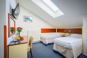 a hotel room with two beds and a desk with a tv at Hotel Atos in Prague +44 photos
