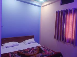 a bedroom with a bed with purple walls and a window at Tridev paying guest house in Varanasi
