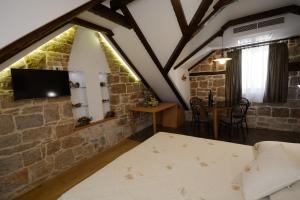 1 dormitorio con pared de piedra, cama y mesa en Villa Desideria, en Split