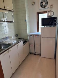 Una pequeña cocina con nevera y microondas. en Dogo Comfort Stay 201, en Matsuyama