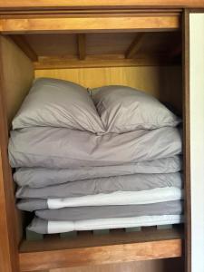 Una cama con sábanas grises y almohadas en un armario. en Dogo Comfort Stay 201, en Matsuyama