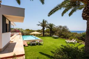 a backyard with a swimming pool and a lawn with chaise lounge chairs at Villa Rosa in Punta Prima