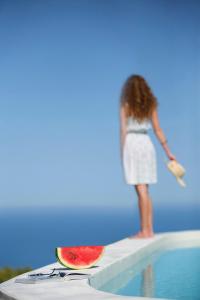 a woman standing next to a pool with a slice of watermelon at Boo Premium Living Villen Auf Lefkada in Tsoukaladhes