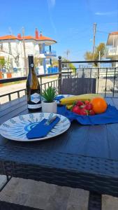 a table with a bottle of wine and a plate of fruit at Alex Studios Paralia Vrasna in Asprovalta +5 photos