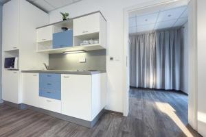 a kitchen with white cabinets and a large window at Aparthotel DKS in Chomutov