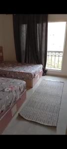 a bedroom with two beds and a window and a rug at 3BR furnished apartment in Madinaty B1 شقة مفروشة 3 غرف نوم في مدينتي in Madinaty
