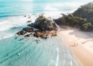 eine Luftaufnahme eines Strandes mit Menschen im Wasser in der Unterkunft Cape Vue - Vue 5 Byron Bay in Ewingsdale + 3 Fotos
