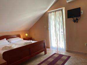 a bedroom with a bed with a television and a window at Vila Ćorović in Kumbor