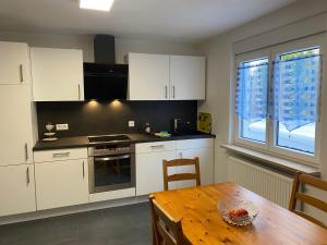 a kitchen with white cabinets and a wooden table at Ferienwohnung Bianca in Ettenheim