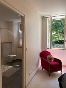 ein Badezimmer mit einem roten Stuhl und einem WC in der Unterkunft La marmotte in Le Vanneau